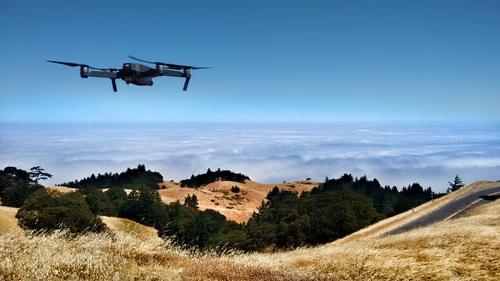 一架无人驾驶飞机在长满草的山上盘旋